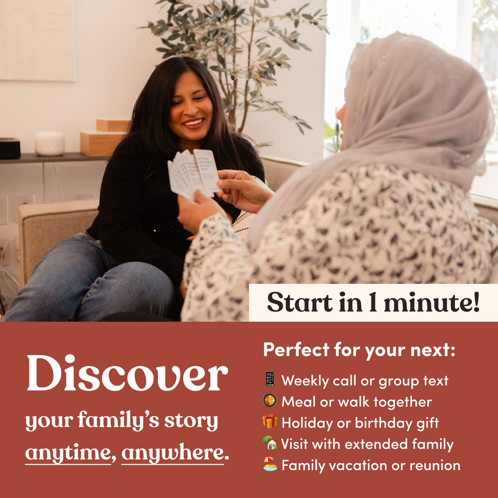 Two women on a couch, one showing question cards to the other, headline “Discover your family's story anytime, anywhere”