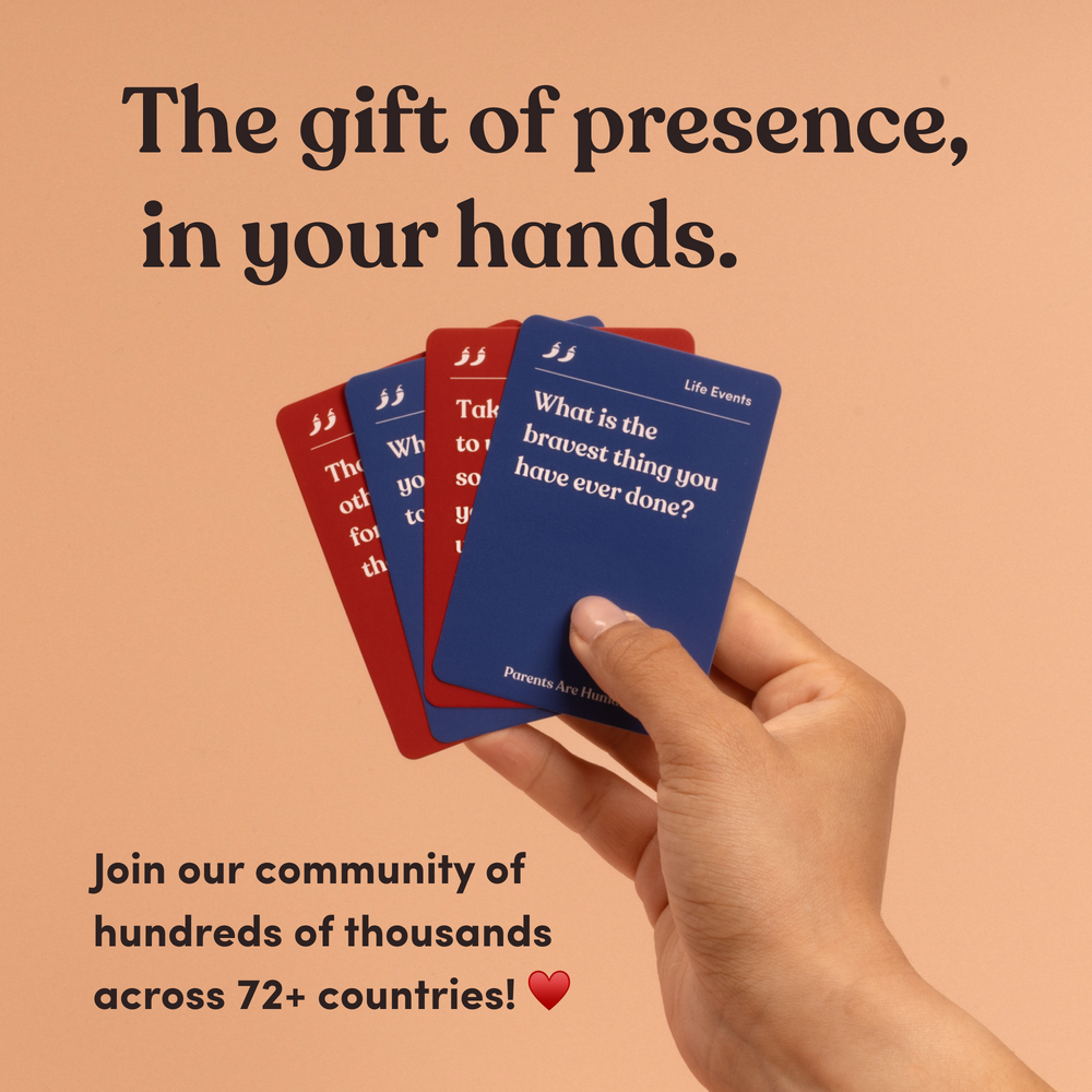 A hand holding a fan of four red and blue Parents Are Human question cards, headline “The gift of presence, in your hands”