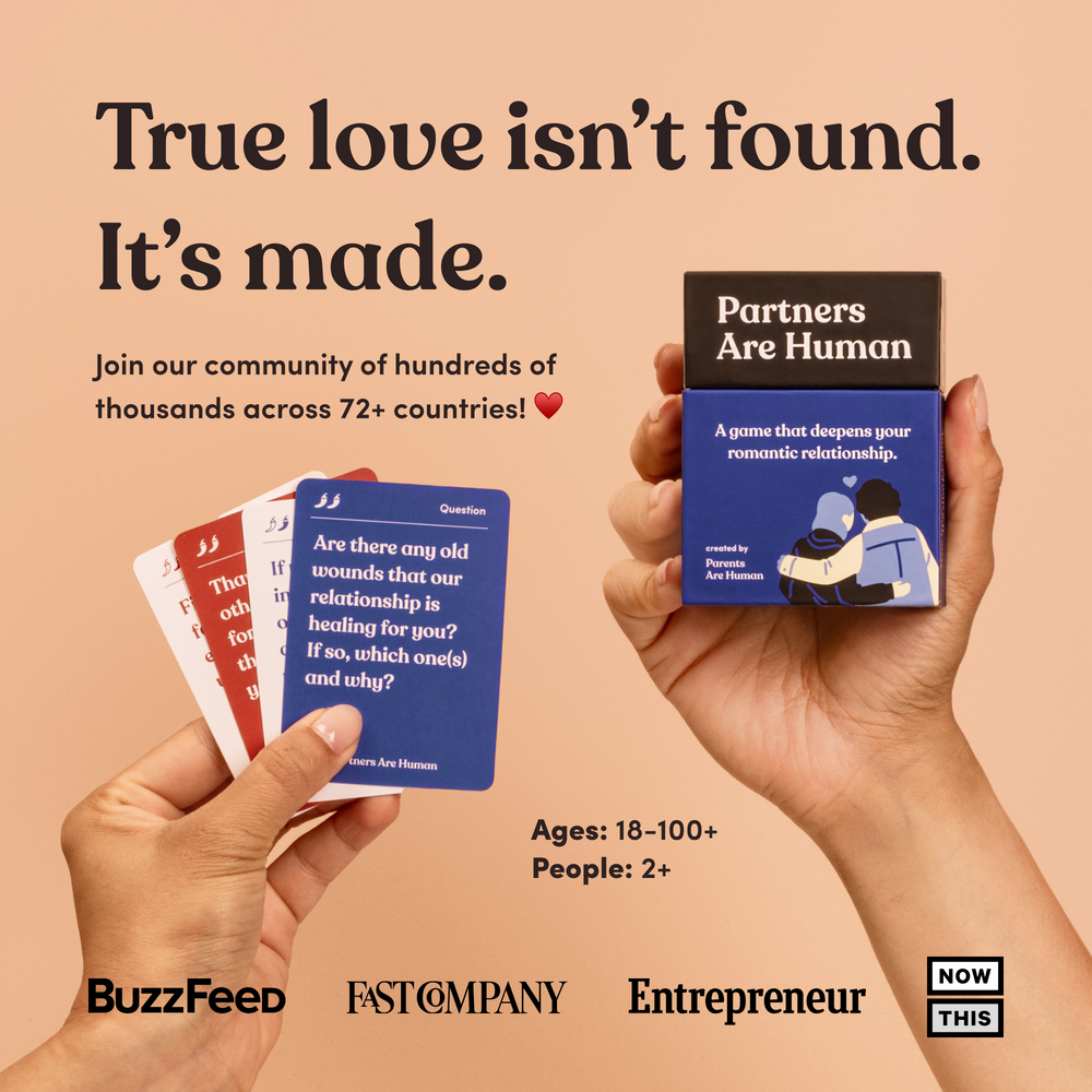 Two hands hold fanned question cards and the Partners Are Human box, headline “True love isn't found. It's made”