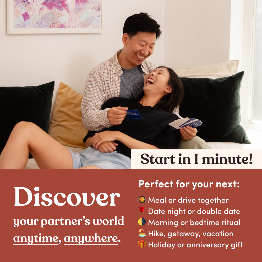 A couple laughing together on a couch while holding question cards, headline “Discover your partner's world anytime, anywhere”