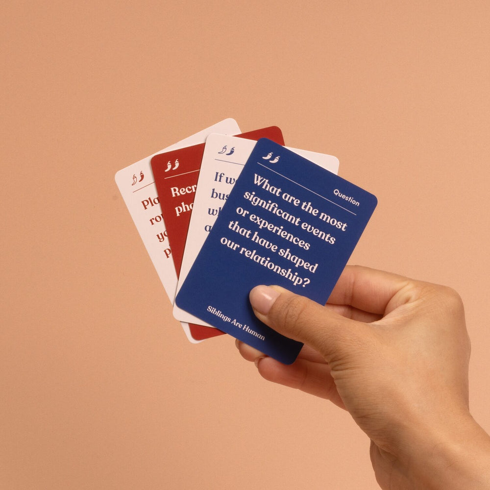 Hand fanning Siblings Are Human cards; top card asks what events or experiences have shaped our relationship